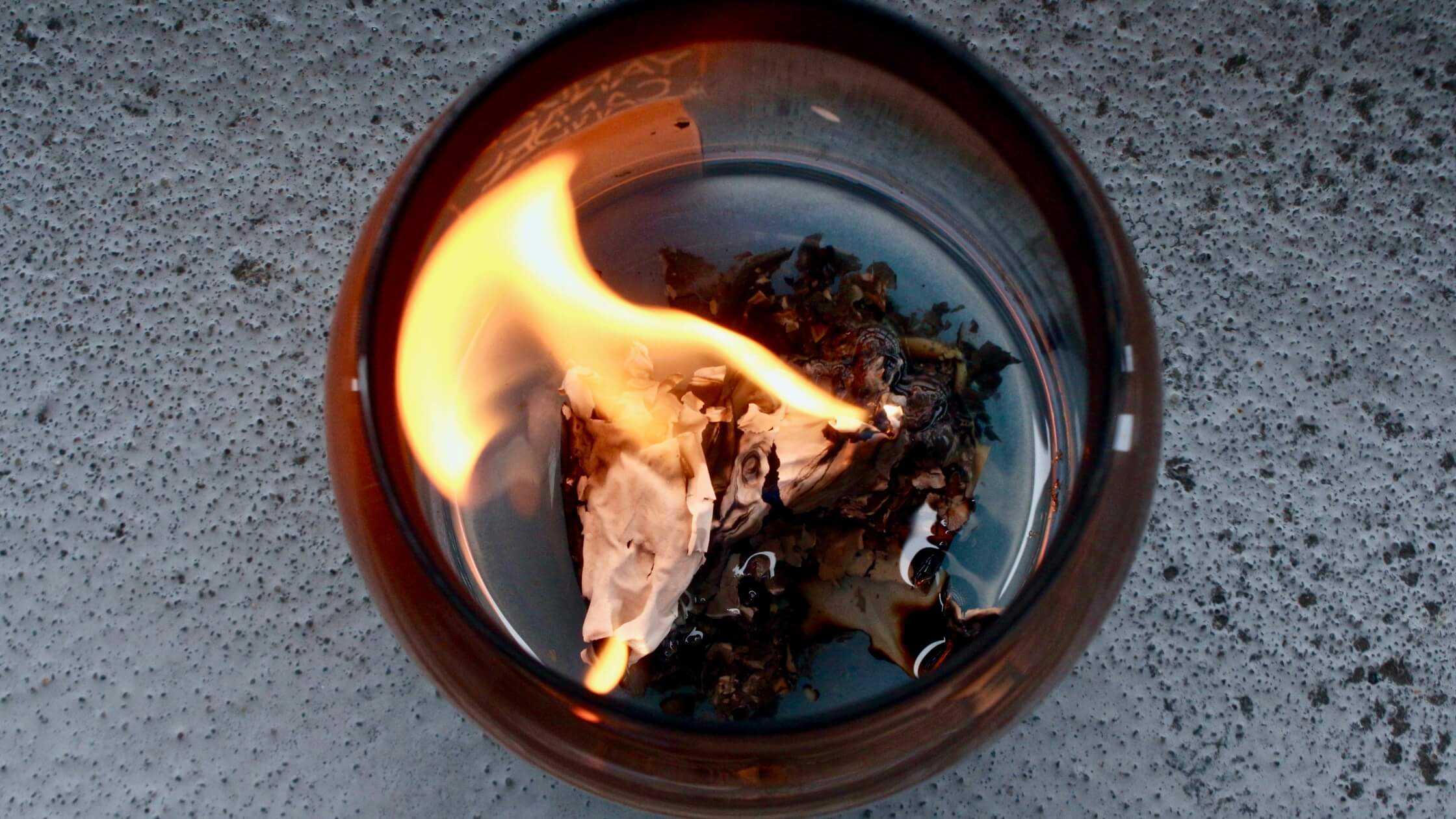 Brennendes Papier in feuerfester Schale, symbolisch für Loslassen