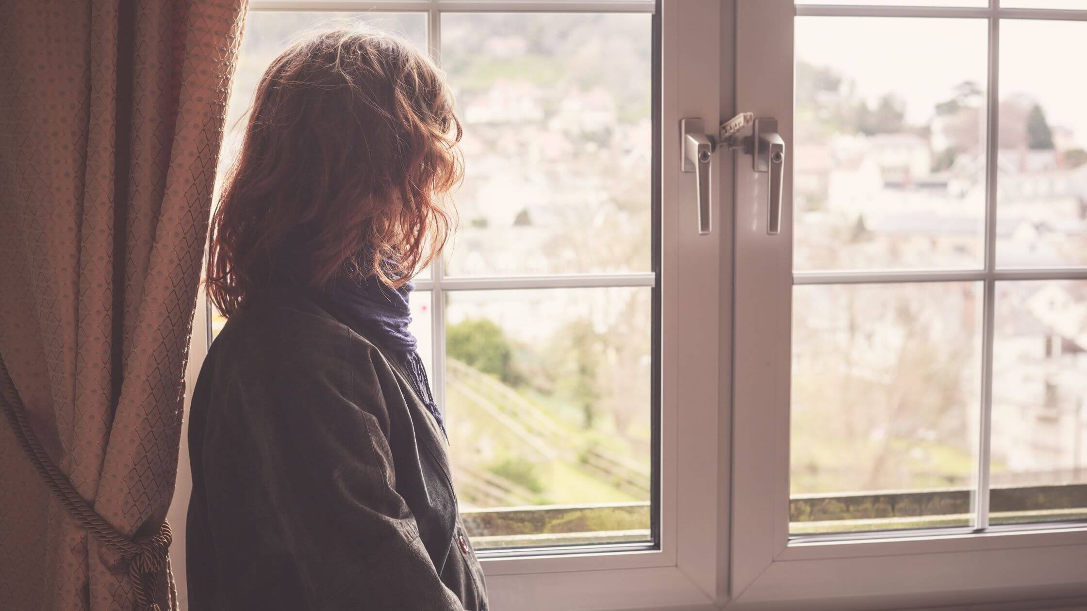 Nachdenkliche Frau am Fenster im Morgenlicht – symbolisiert Selbstreflexion und den Beginn der Human Design Reise