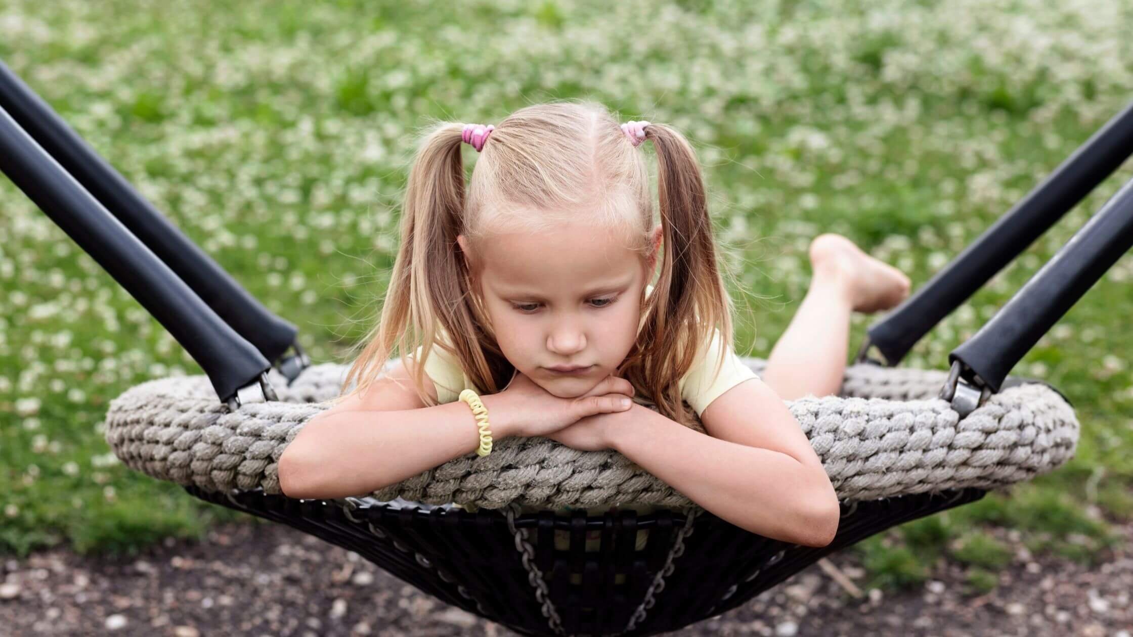 Nachdenkliches Kind allein auf Schaukel – symbolisiert frühe Kindheitsprägungen und deren Einfluss auf heutiges Verhalten