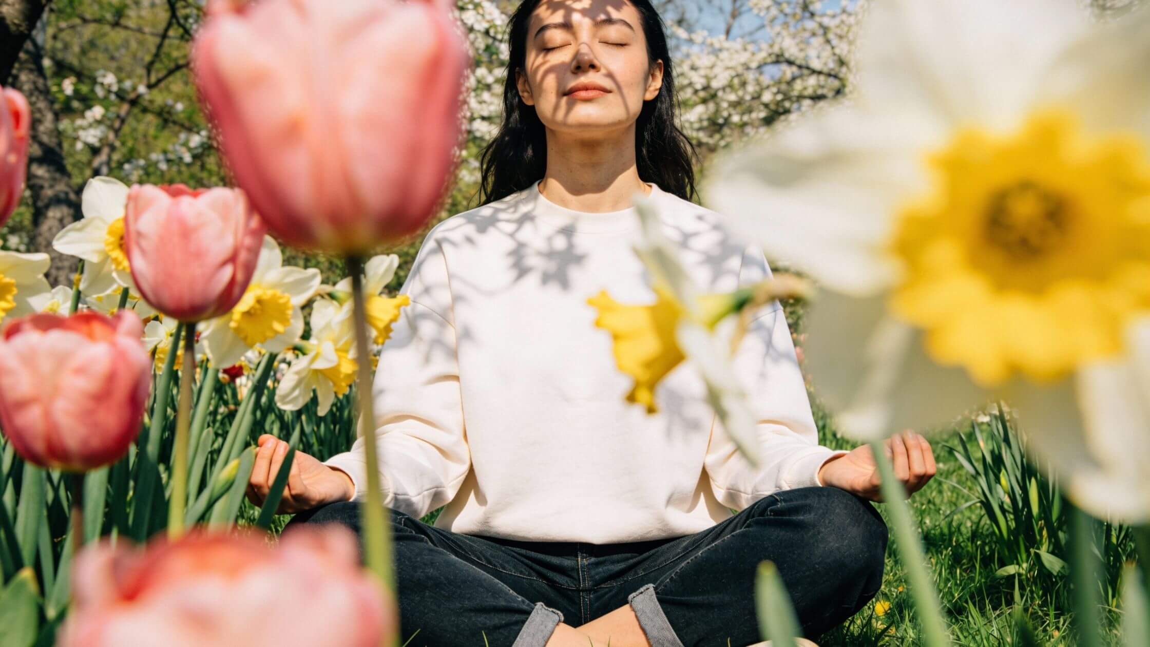 Frau meditiert im Frühlingsgarten zu Ostara für innere Balance