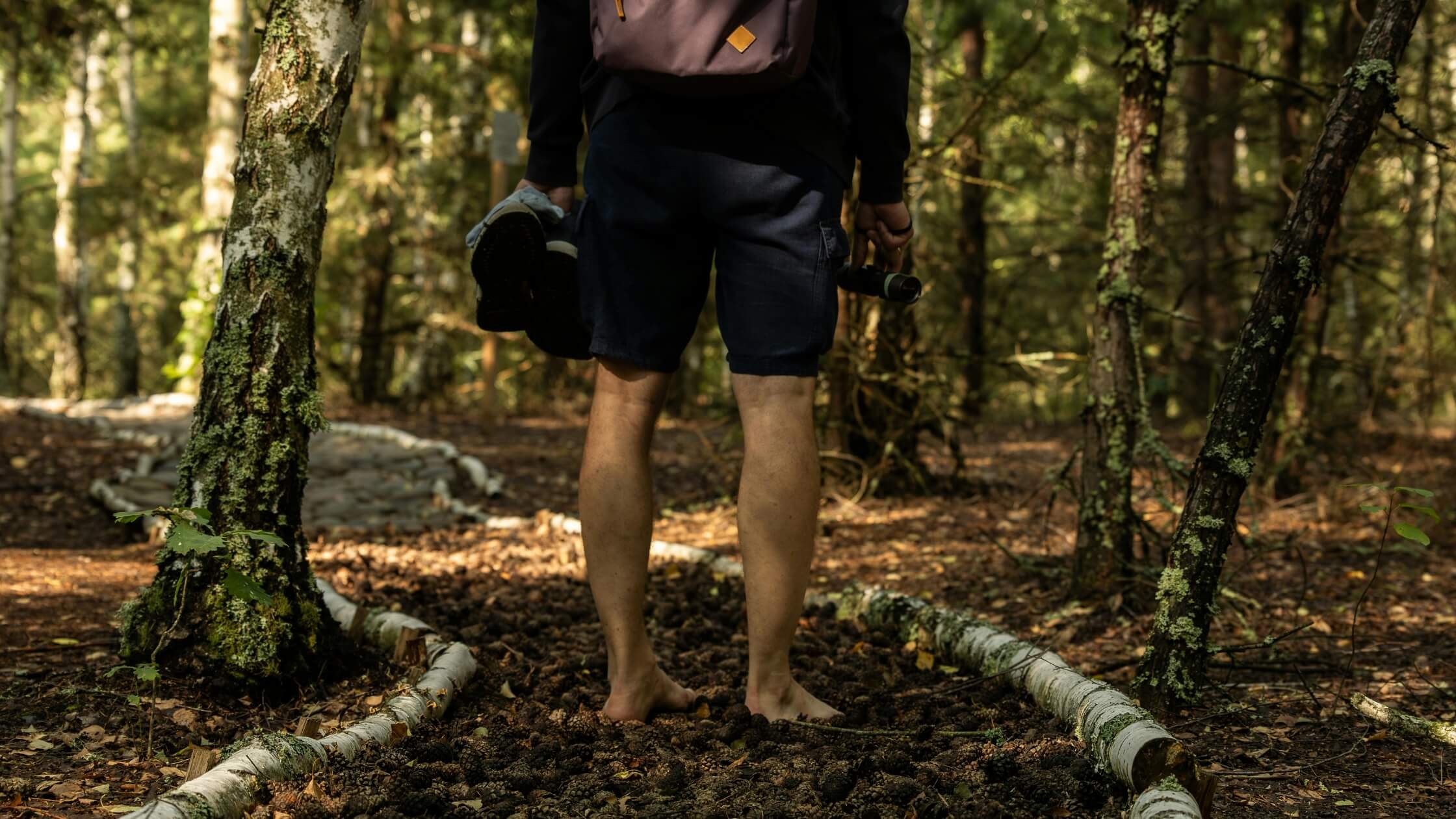 Frau praktiziert Körperwahrnehmung barfuß im Wald für Geomantie-Übung, Augen geschlossen