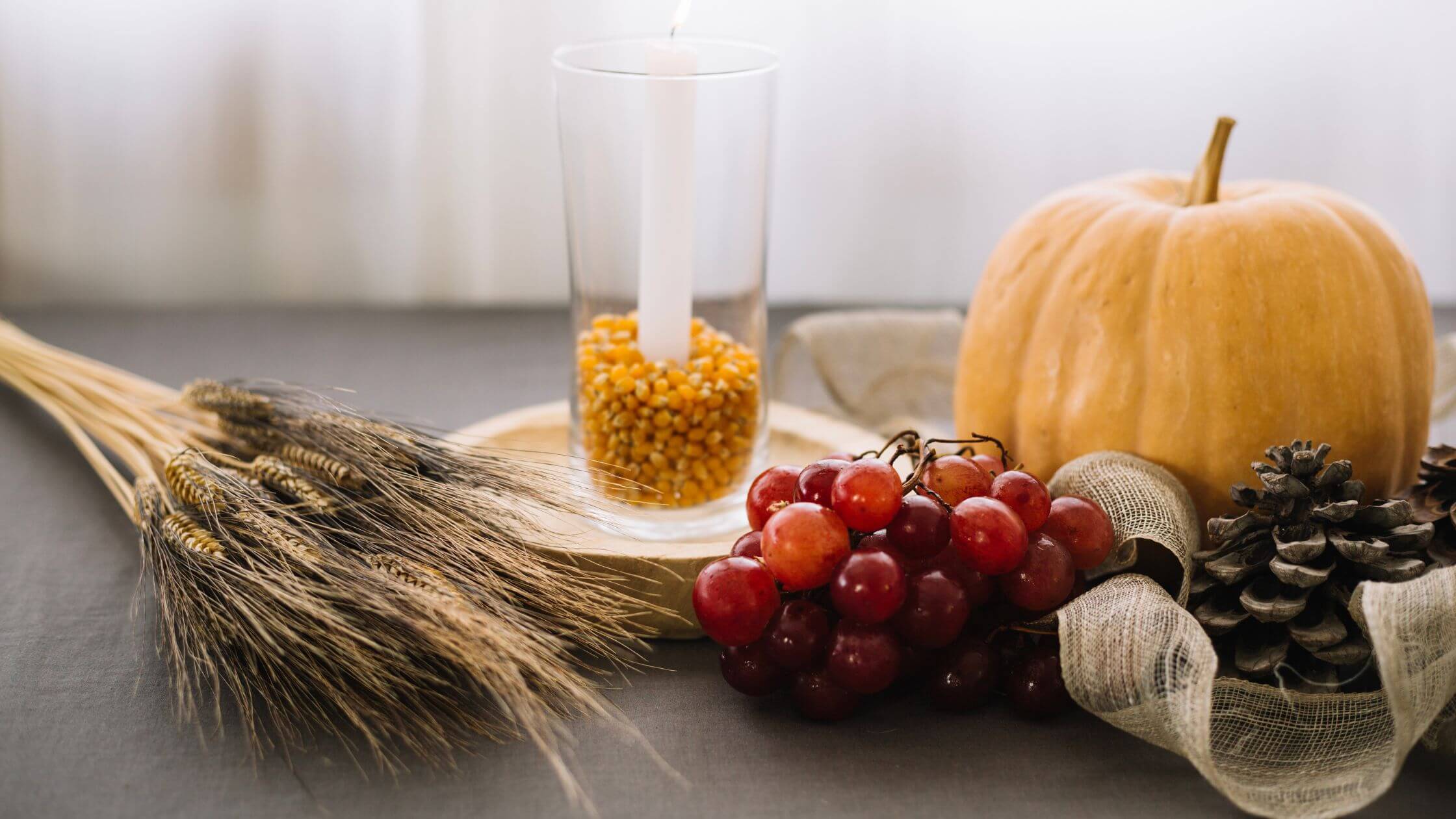 Lughnasadh feiern Rituale Kräuter und Rezepte Lughnasadh Altar mit Ähren, Kerze und Sichel auf dunklem Tuch