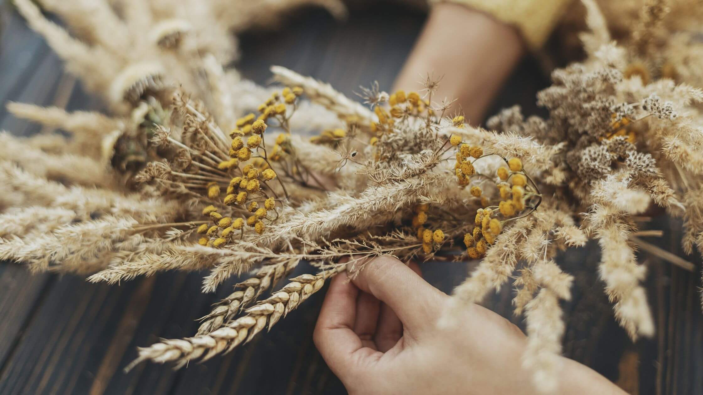 Lughnasadh feiern Rituale Kräuter und Rezepte Hände flechten Grashalm-Zopf für Loslassungsritual