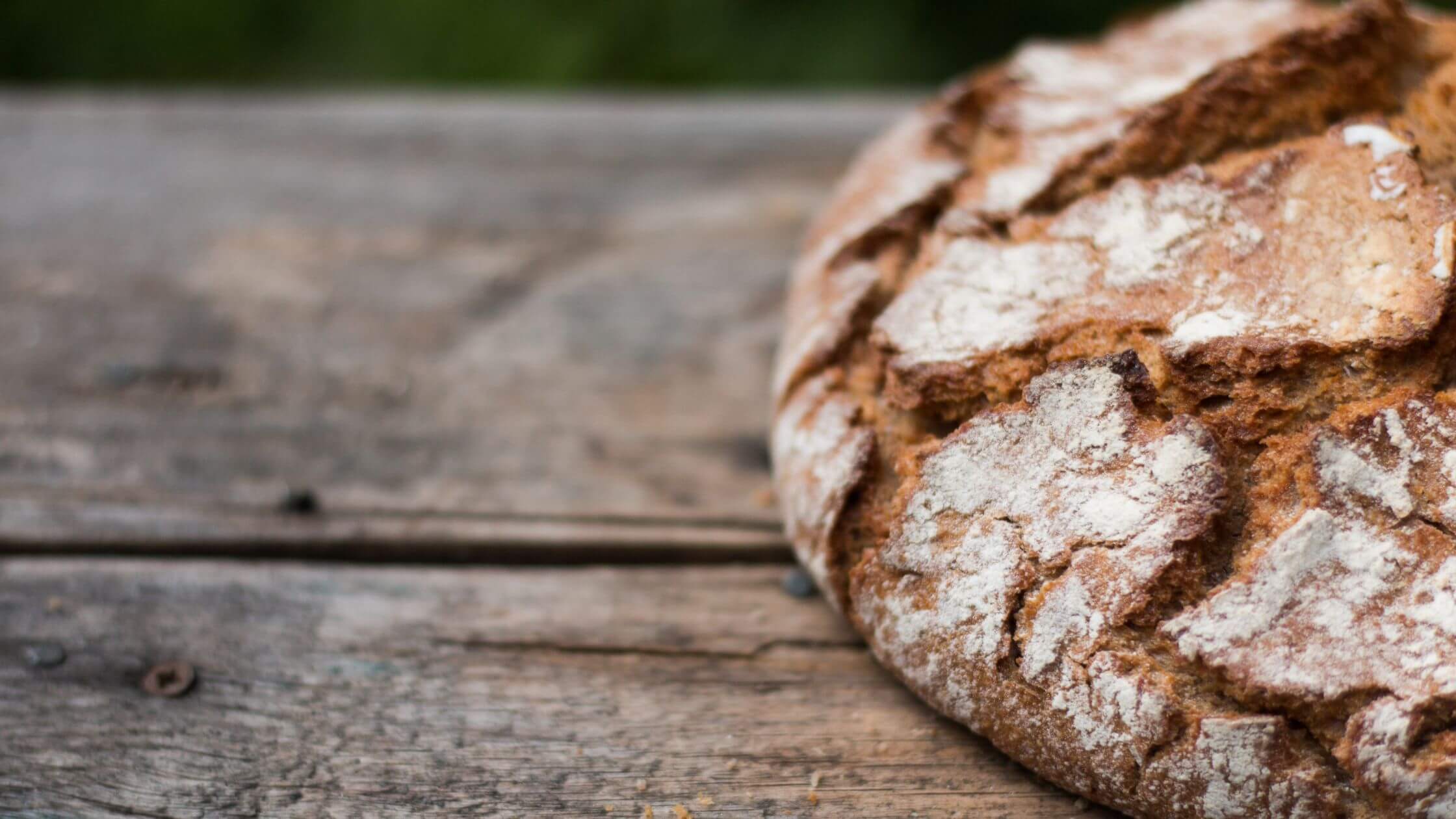 Rustikaler Brotlaib auf Holztisch – Lammas Fest des ersten Brotes