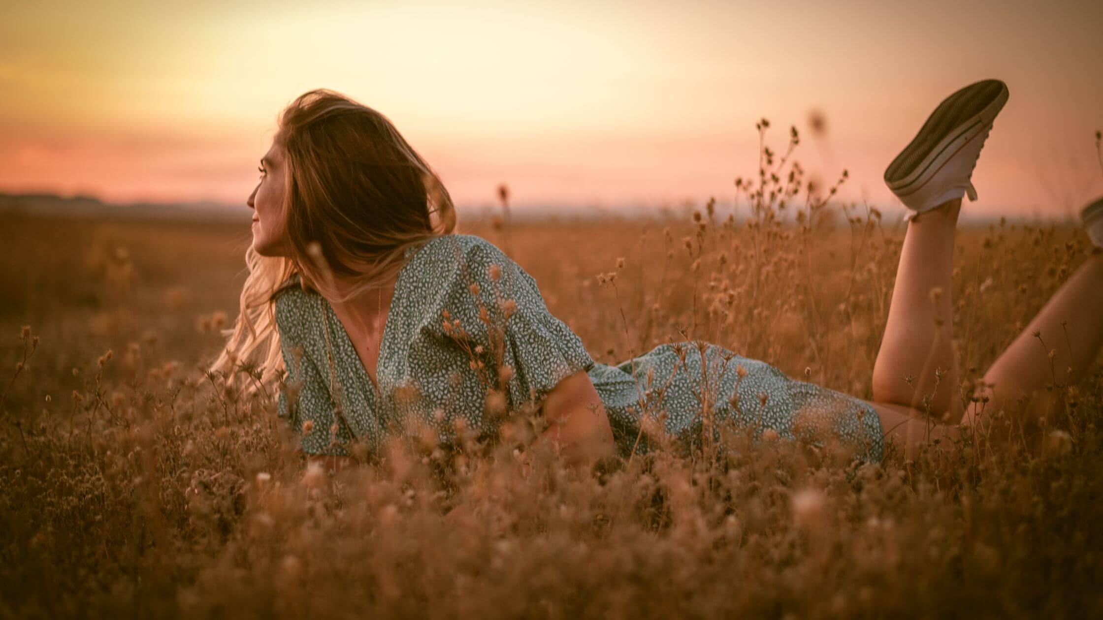 Lughnasadh feiern Rituale Kräuter und Rezepte Frau liegt entspannt auf Sommerwiese – Lughnasadh Meditation in der Natur